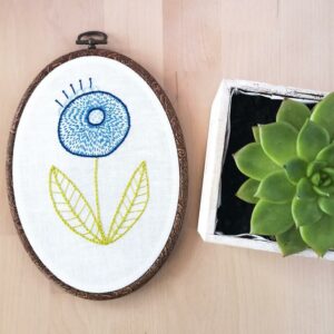 Blue modern flower hand embroidery in an oval hoop