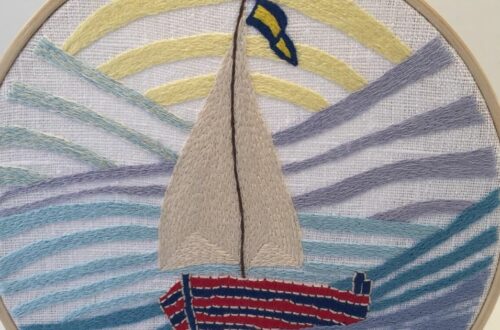 Hand embroidered sail boat with a sail and a flag
