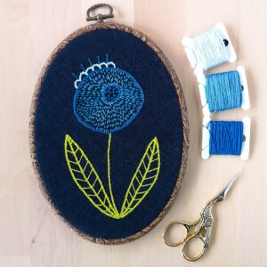 Blue hand embroidered flower on navy blue linen in the hoop