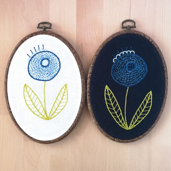2 hoops with hand embroidered blue flower on different fabrics, white and navy blue